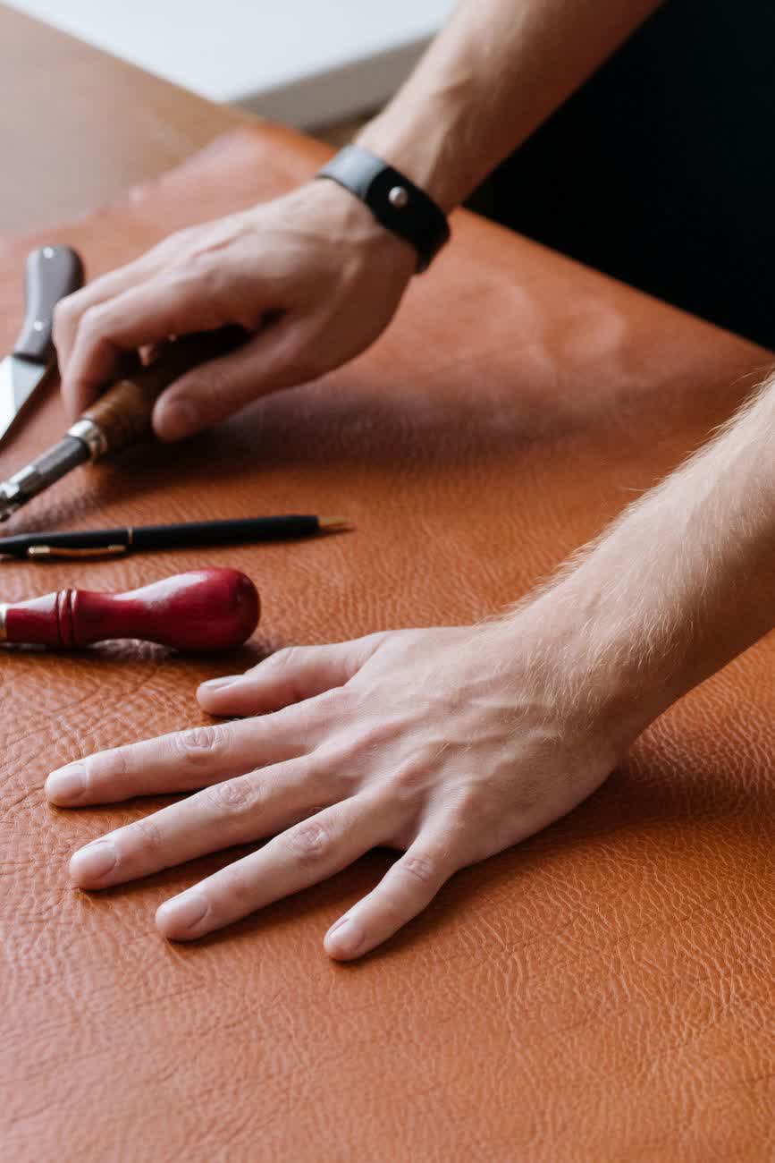 Ruce při ruční práci s kůží v ateliéru Handmora